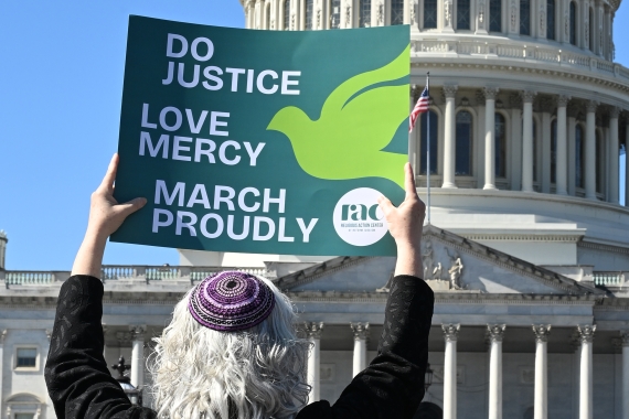 Woman with kippah holding up sign in front of the Capitol building