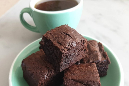 Chocolate chip cappuccino brownies on a blue plate with a cup of coffee in the background