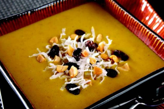 Golden colored Indian Mulligatawny soup topped with raisins and coconut