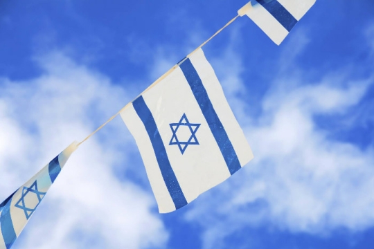 String of Israeli flags against a cloudy blue sky