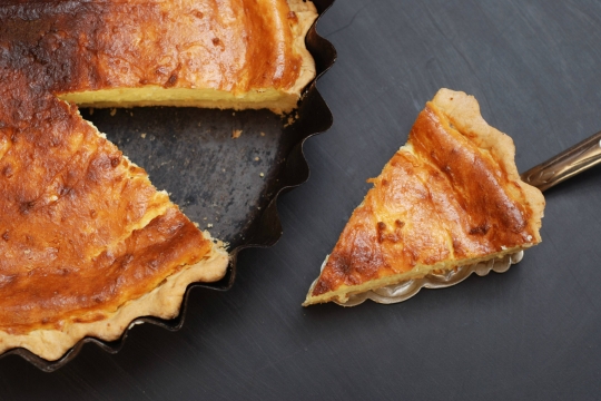 Half of a melopita honey and cheese pie with a slice cut out