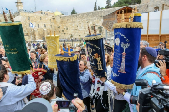 Group of people holding up Torah scrolls in a protest at the Western Wall