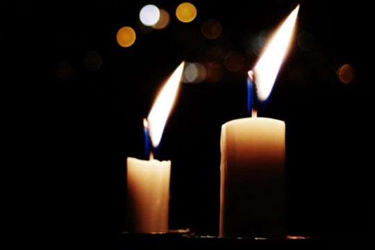 Two Shabbat candles glowing in the darkness