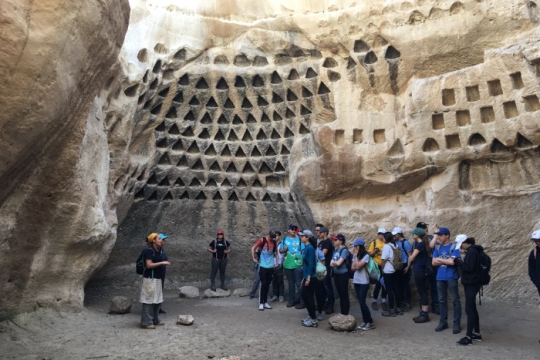 Group of students standing in an ancient cave with a teacher at the front 