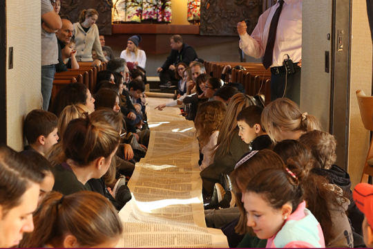 group of teens looking at the Torah scroll
