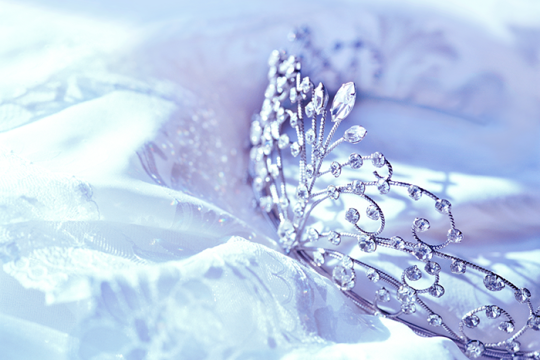 A silver tiara sitting on a white tablecloth