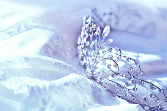 A silver tiara sitting on a white tablecloth 