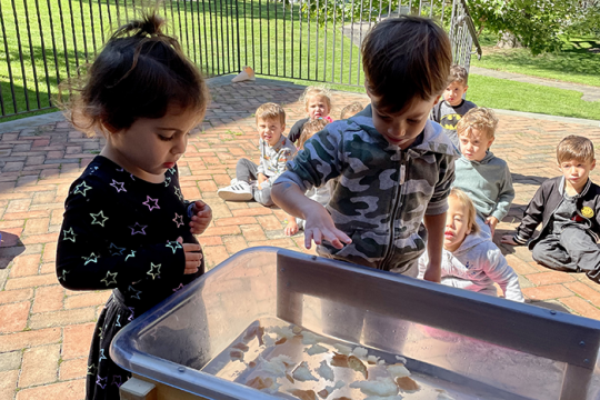 an image of a toddler boy and girl playing while other kids watch in the background