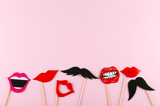 Photo of paper lips and mustaches on sticks that look like they are laughing