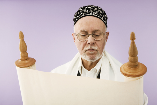 Photo of an older man standing behind a Torah scroll