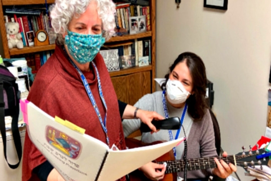 Cantor Laura Stein and Rabbi Sandy Bogin lead Shabbat worship services behind the loudspeaker Cantor Laura Stein and Rabbi Sandy Bogin lead Shabbat worship services behind a loudspeaker