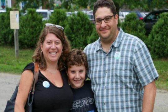 A mother and father and their son smiling while visiting camp