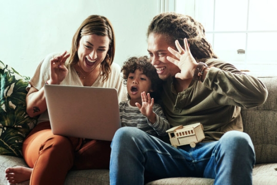 Multi-racial family gathered enthusiastically around a computer