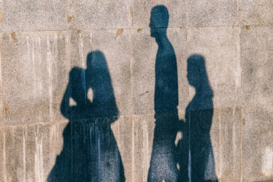 Shadows of a four person family cast upon a cement wall