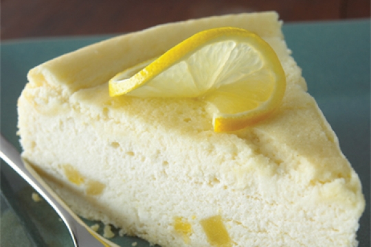fluffy slice of cheesecake with a slice of lemon as garnish