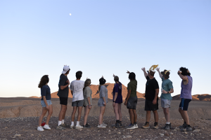 Photo of a group of teens atop Masada pointing behind them