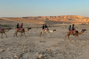 Photo of teens riding camals in Kfar Hanokdim