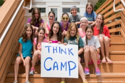 Campers siting on cabin steps holding a THINK CAMP sign