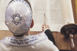 A Jewish boy reading the Torah and wearing a kippah