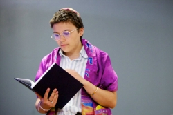 Person wearing a purple prayer shawl and holding a prayer book