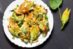 Pile of fried stuffed zucchini blossoms on a white plate 