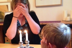 mom blessing Shabbat candles while son looks on