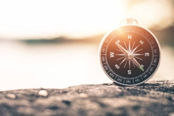 Compass facing north sitting on a rock with the sky in the background