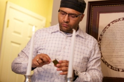 Young Black Jewish man lighting Shabbat candles