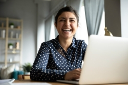 Smiling woman sitting at a laptop in her home 