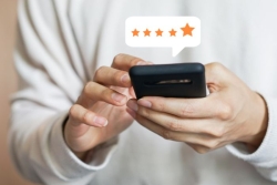 Hands holding an iPhone with a five star rating above it