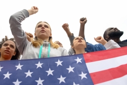 People holding a US flag with their fists in the air