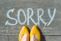 female-feet-with-text-sorry-written-on-asphalt