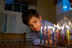child looking at the lit candles on a Chanukah menorah