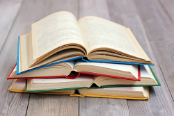 yellow, green, red and blue books open and stacked on top of each other