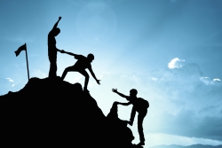 People helping each other climb a mountain peak
