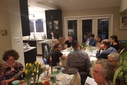 an image of a a group of people sitting down at two tables having a passover seder