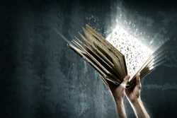 two white hands holding a book against a dark background with light coming from the book and letters floating off the page 