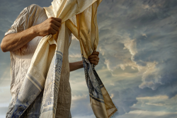 an image of a man holding a tallit over his head while praying