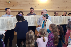 an image of people holding open the Torah scroll on Simchat Torah