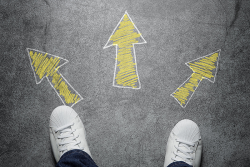 Photo of two feet, standing on the ground, with three yellow arrows pointing in different directions