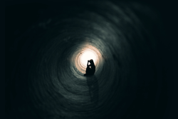 Photo of a worried person sitting in a dark tunnel