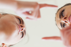 Photo of two faces and hands, each pointing at the other