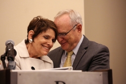 Rabbis Lynne Landsberg and David Saperstein share a moment at a podium, both smiling, heads leaned towards one another.