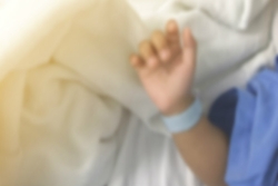 Babys arm on hospital blankets wearing a blue hospital ID bracelet around its wrist
