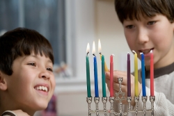 Two young boys lighting a Hanukkah menorah