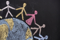 Chalk drawing of a globe with different colors of stick figures standing atop it