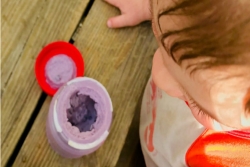 Closeup of a child looking down on a container of blueberry ice cream on a picnic table 