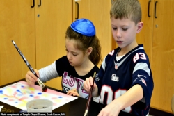 Two children painting together and one of them is wearing a kippah