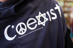 Back of a sweatshirt with COEXIST written with religious symbols