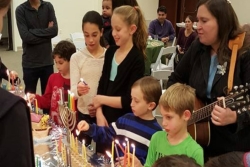 Children light the menorah at a congregational Hanukkah party 